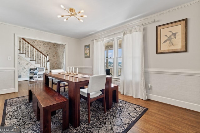 dining space with stairway, a notable chandelier, wood finished floors, and wainscoting