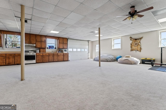 basement with a drop ceiling, light colored carpet, and ceiling fan