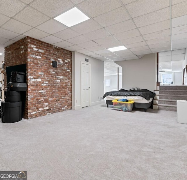 below grade area featuring carpet flooring, brick wall, a paneled ceiling, and visible vents