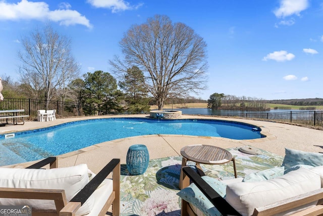 view of pool with a patio area, a water view, a pool with connected hot tub, and fence