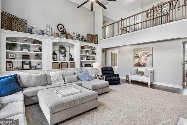 living room featuring a high ceiling, wood finished floors, baseboards, and ceiling fan