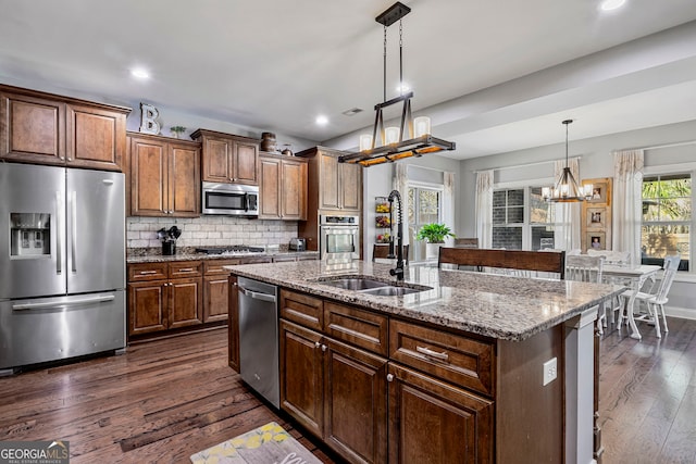 kitchen featuring tasteful backsplash, a sink, a notable chandelier, stainless steel appliances, and dark wood-style flooring