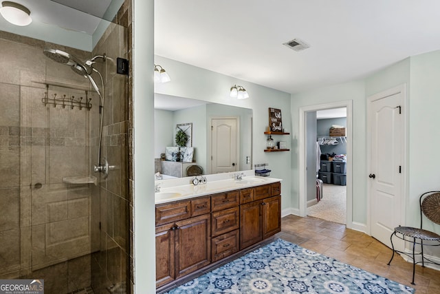 bathroom featuring double vanity, visible vents, tiled shower, and a sink