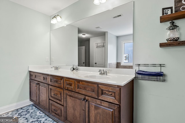 full bath featuring a sink, visible vents, baseboards, and double vanity