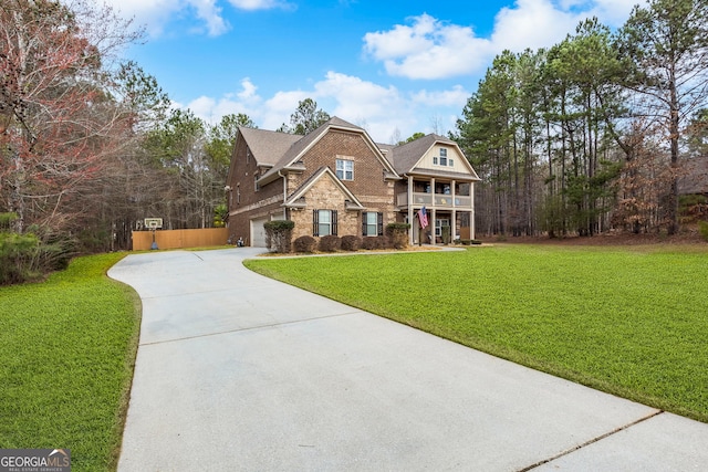 view of front of house featuring a balcony, concrete driveway, a front yard, an attached garage, and brick siding