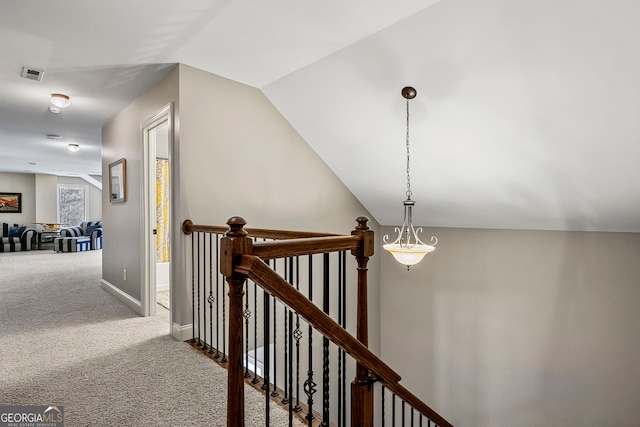 corridor featuring visible vents, baseboards, vaulted ceiling, carpet flooring, and an upstairs landing