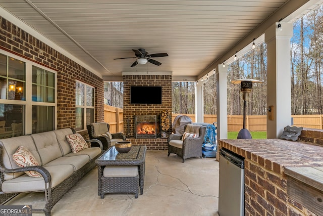 view of patio with an outdoor living space with a fireplace, an outdoor kitchen, ceiling fan, and fence