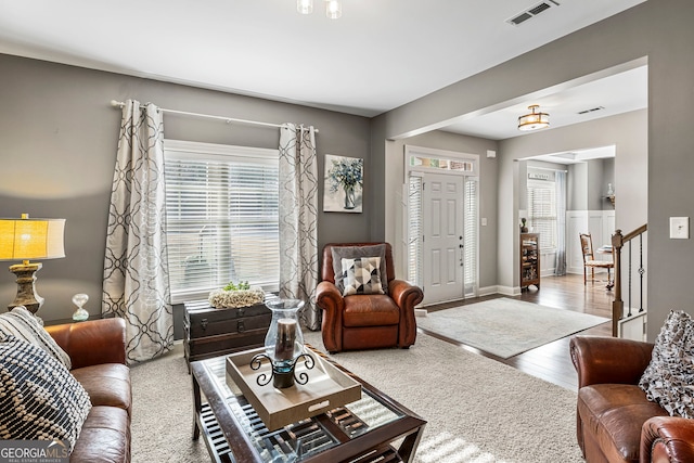 living room with visible vents, baseboards, wood finished floors, and stairs