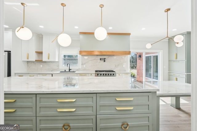 kitchen featuring green cabinets, decorative backsplash, wall chimney exhaust hood, and a sink