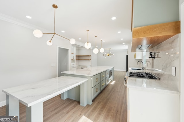 kitchen with open shelves, crown molding, light wood-style floors, a large island, and a sink