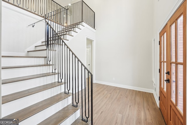 foyer entrance with a wealth of natural light, stairs, baseboards, and wood finished floors