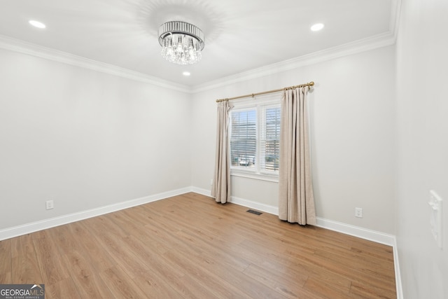 empty room with visible vents, ornamental molding, an inviting chandelier, light wood finished floors, and baseboards