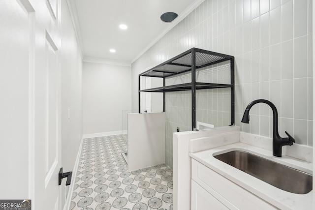 washroom featuring crown molding, baseboards, recessed lighting, tile walls, and a sink