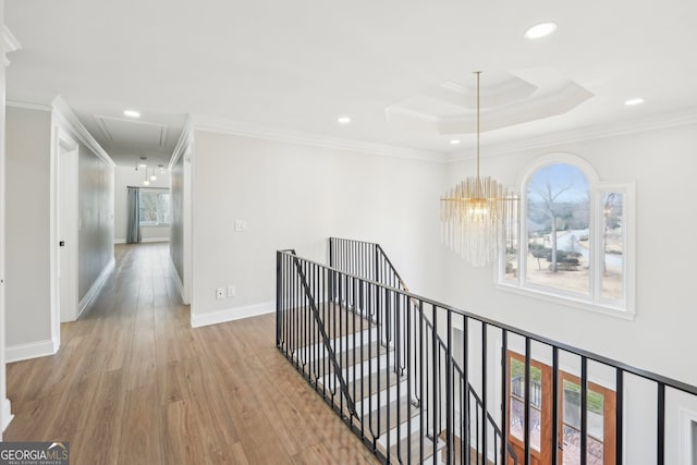 corridor with an upstairs landing, attic access, crown molding, and wood finished floors