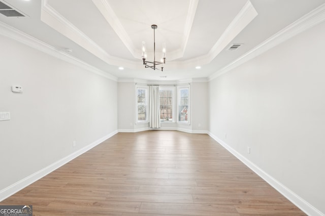 interior space featuring visible vents, baseboards, light wood-type flooring, a tray ceiling, and a notable chandelier