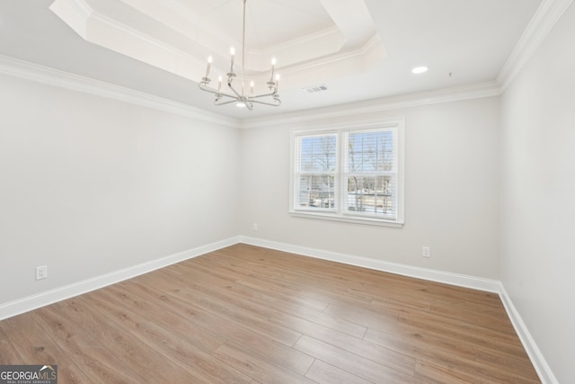 empty room with visible vents, ornamental molding, wood finished floors, a raised ceiling, and a chandelier