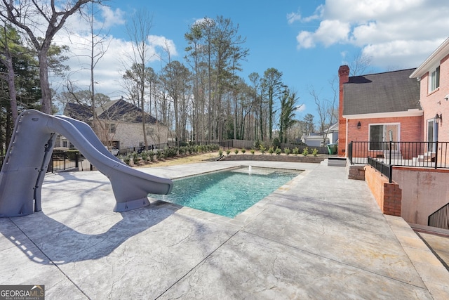 view of pool featuring fence, a patio area, a fenced in pool, and a water slide