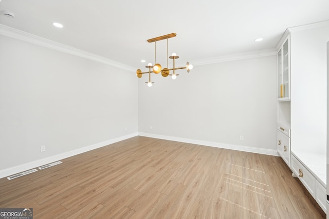 spare room with an inviting chandelier, crown molding, visible vents, and light wood finished floors