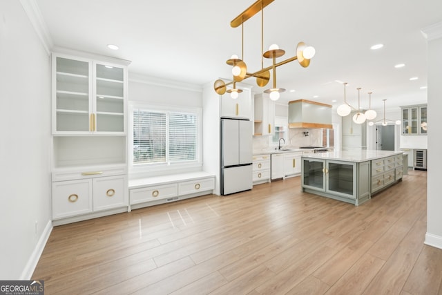 kitchen with a sink, white cabinetry, white appliances, crown molding, and light wood finished floors