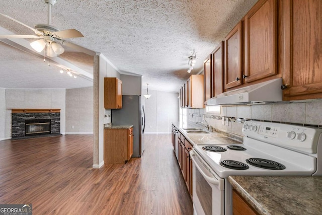 kitchen featuring electric range, brown cabinets, and under cabinet range hood