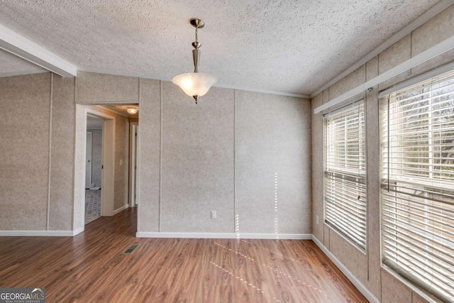 unfurnished dining area with baseboards, a textured ceiling, wood finished floors, and vaulted ceiling with beams