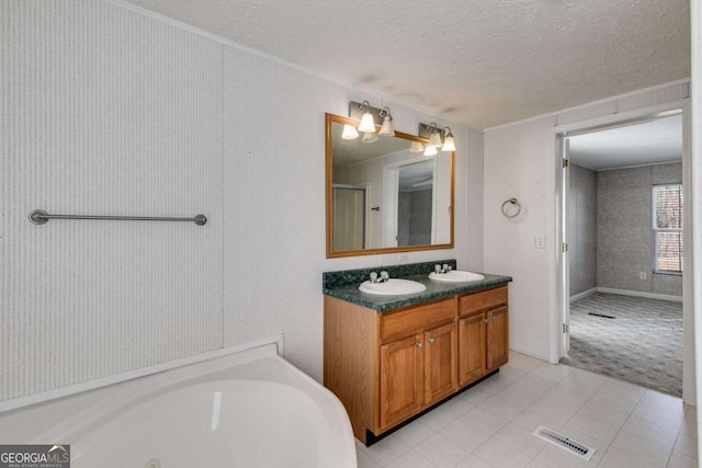 bathroom with visible vents, a jetted tub, double vanity, a textured ceiling, and a sink