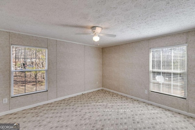 carpeted spare room with a ceiling fan, baseboards, and a textured ceiling