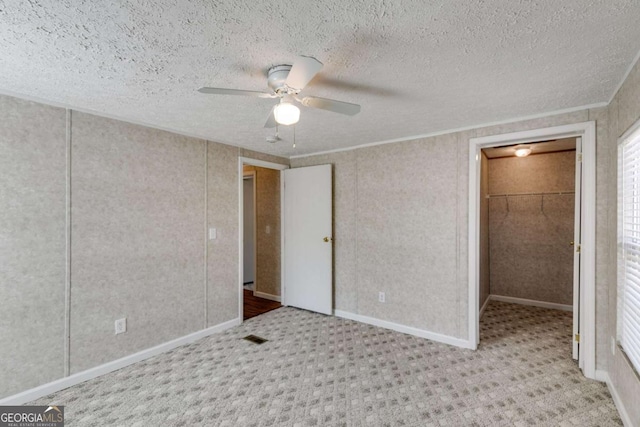 unfurnished bedroom with visible vents, baseboards, ceiling fan, ornamental molding, and a textured ceiling