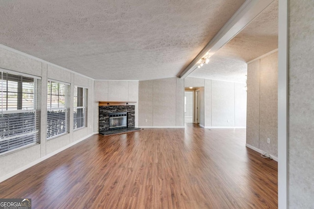 unfurnished living room with lofted ceiling with beams, ornamental molding, wood finished floors, and a textured ceiling