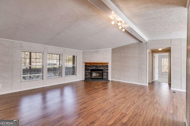 unfurnished living room with beam ceiling, wood finished floors, and a textured ceiling