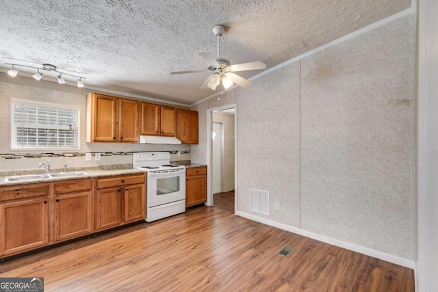 kitchen with light wood finished floors, visible vents, brown cabinets, white electric range oven, and a sink