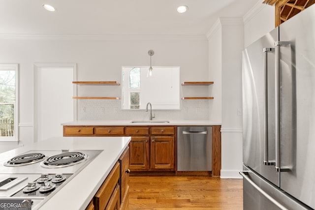 kitchen with open shelves, a sink, stainless steel appliances, crown molding, and brown cabinets