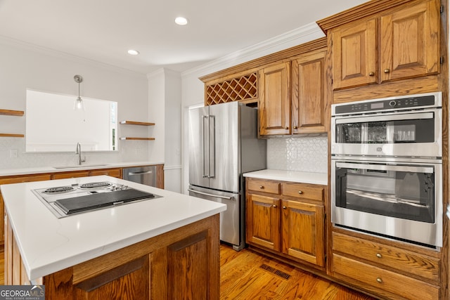 kitchen with a sink, ornamental molding, brown cabinets, appliances with stainless steel finishes, and open shelves