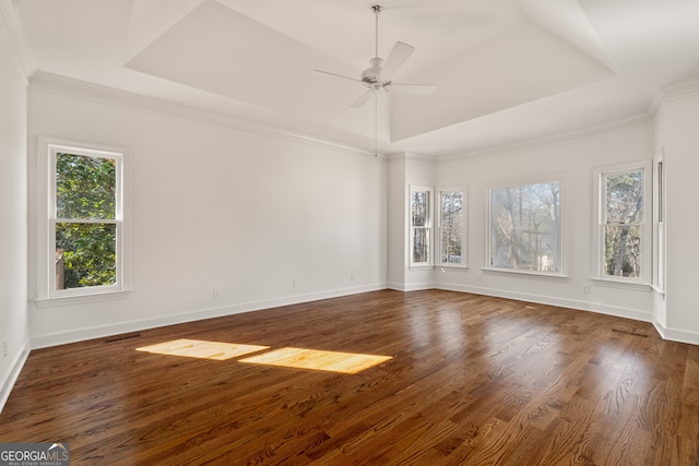 unfurnished room with a tray ceiling, wood finished floors, baseboards, and ceiling fan