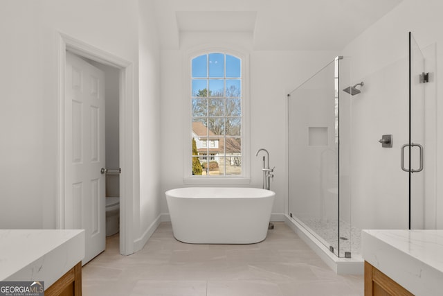 full bathroom with vanity, baseboards, a freestanding tub, a shower stall, and toilet