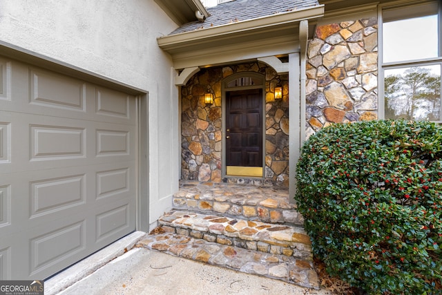 entrance to property featuring an attached garage and stone siding