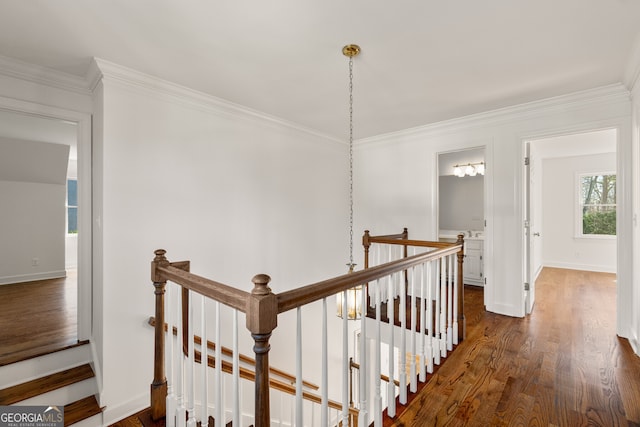 hallway featuring an upstairs landing, dark wood finished floors, baseboards, and ornamental molding