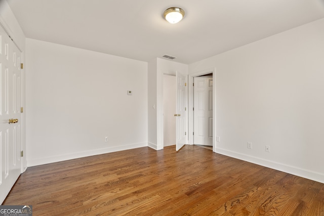 unfurnished bedroom featuring visible vents, baseboards, and wood finished floors