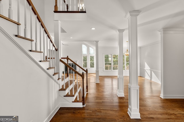 foyer entrance featuring wood finished floors, recessed lighting, stairway, baseboards, and ornate columns