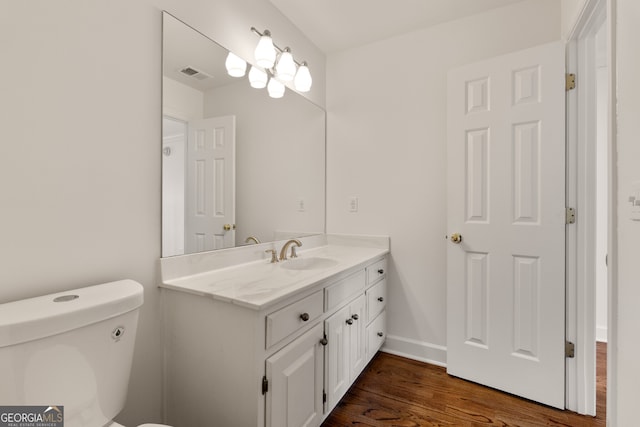 bathroom with vanity, wood finished floors, visible vents, baseboards, and toilet