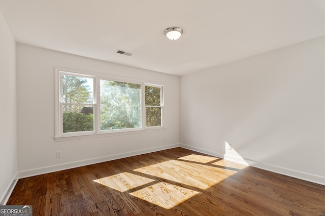 empty room with visible vents, baseboards, and wood finished floors