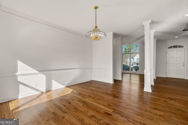 unfurnished dining area featuring crown molding, wood finished floors, and ornate columns