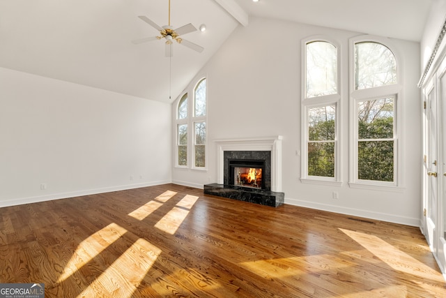 unfurnished living room with ceiling fan, wood finished floors, a high end fireplace, and high vaulted ceiling