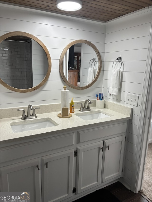 bathroom with a sink, wooden ceiling, double vanity, and wood walls