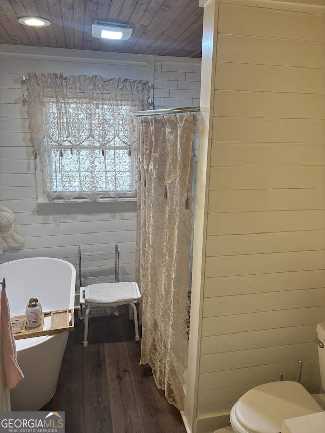 bathroom with toilet, wood finished floors, wood walls, a freestanding bath, and wood ceiling