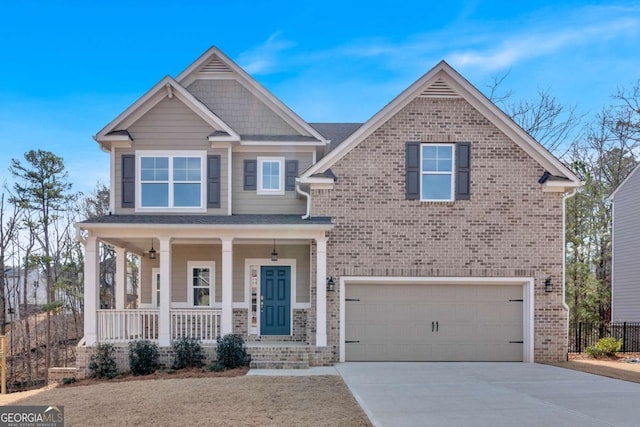 craftsman house with brick siding, an attached garage, covered porch, and driveway