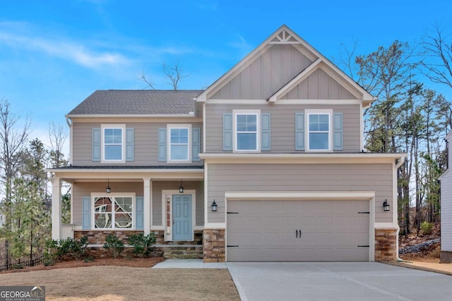 craftsman house with stone siding, an attached garage, concrete driveway, and board and batten siding