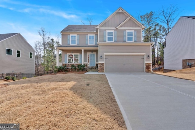 craftsman inspired home featuring an attached garage, covered porch, concrete driveway, stone siding, and board and batten siding