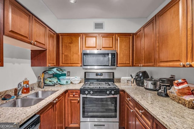 kitchen with light stone counters, visible vents, appliances with stainless steel finishes, and a sink