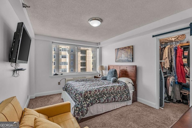 carpeted bedroom with a spacious closet, a closet, a textured ceiling, and baseboards